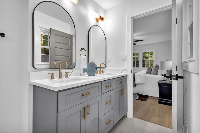 bathroom featuring ceiling fan, ensuite bath, double vanity, and a sink