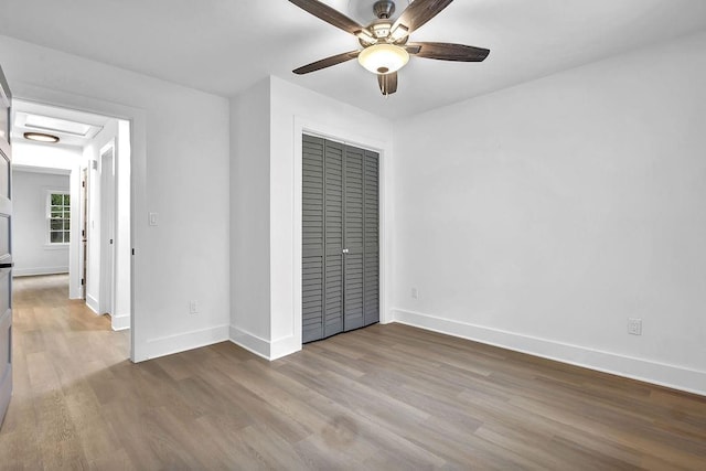 unfurnished bedroom with a closet, a ceiling fan, wood finished floors, and baseboards