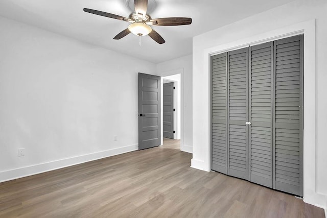 unfurnished bedroom with wood finished floors, ceiling fan, baseboards, and a closet