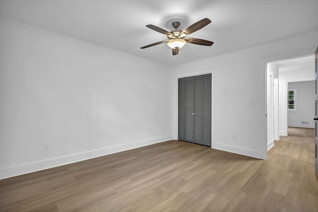 unfurnished bedroom featuring baseboards, wood finished floors, and a closet