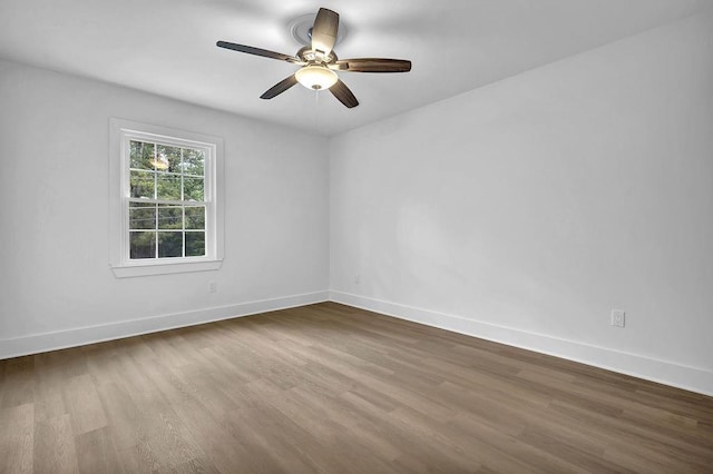 spare room featuring dark wood-type flooring, ceiling fan, and baseboards