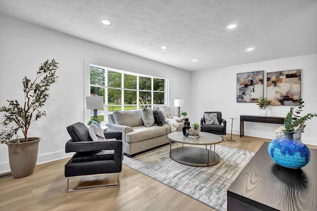 living room with a textured ceiling, wood finished floors, recessed lighting, and baseboards
