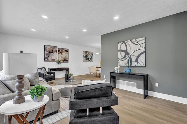 living area featuring visible vents, recessed lighting, light wood finished floors, and baseboards