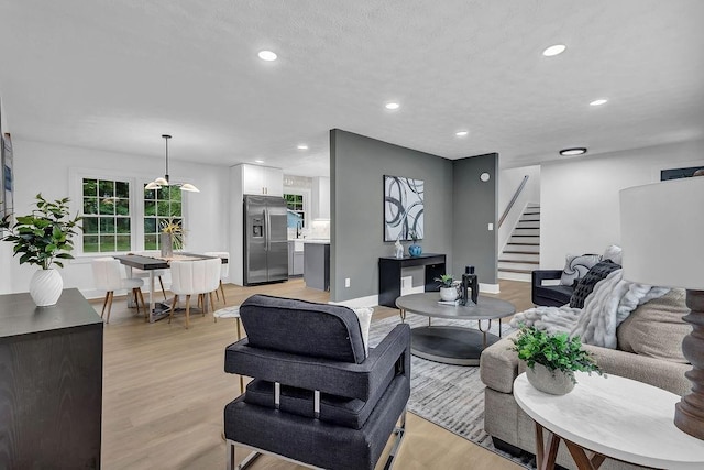 living room with baseboards, stairway, light wood-style floors, and recessed lighting