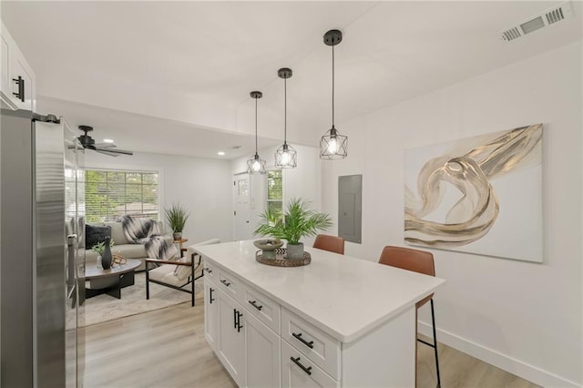 kitchen with white cabinetry, a center island, a kitchen breakfast bar, pendant lighting, and light hardwood / wood-style floors