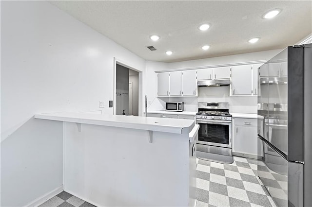 kitchen featuring stainless steel appliances, light countertops, a peninsula, and white cabinetry