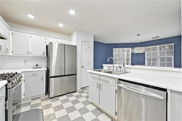 kitchen featuring stainless steel appliances, a sink, light countertops, light floors, and pendant lighting