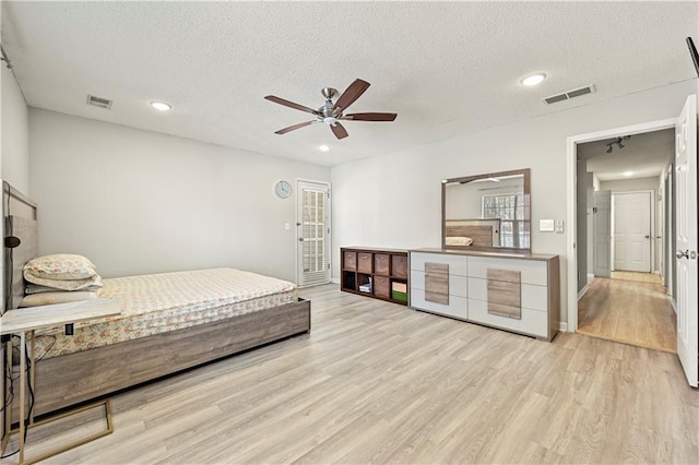 bedroom featuring light wood-style floors, access to exterior, visible vents, and a textured ceiling