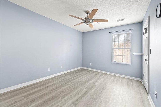 unfurnished room with light wood finished floors, baseboards, visible vents, ceiling fan, and a textured ceiling