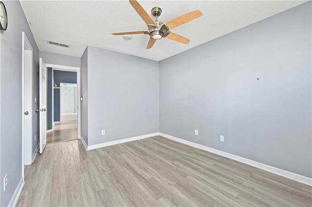 spare room with visible vents, baseboards, a ceiling fan, light wood-style flooring, and a textured ceiling