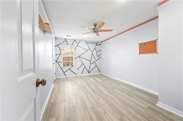 spare room featuring light wood-type flooring, visible vents, and baseboards