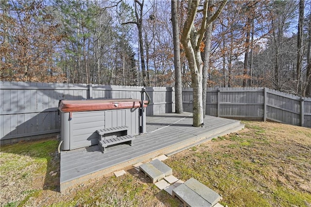 wooden deck featuring a lawn, a fenced backyard, and a hot tub