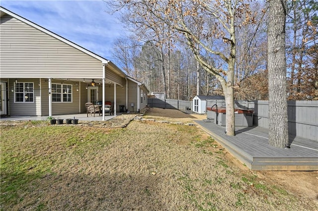 view of yard featuring a hot tub, a patio, ceiling fan, a fenced backyard, and a shed