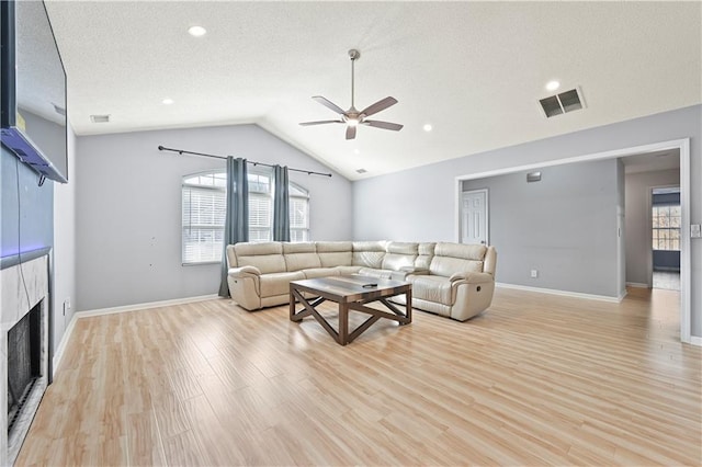 living room featuring visible vents, a fireplace, and light wood finished floors