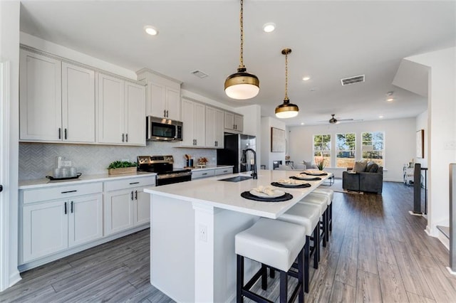 6121 Wayburn St, Tucker, GA 30084 - kitchen with appliances with stainless steel finishes, light countertops, a center island with sink, a breakfast bar area, and open floor plan