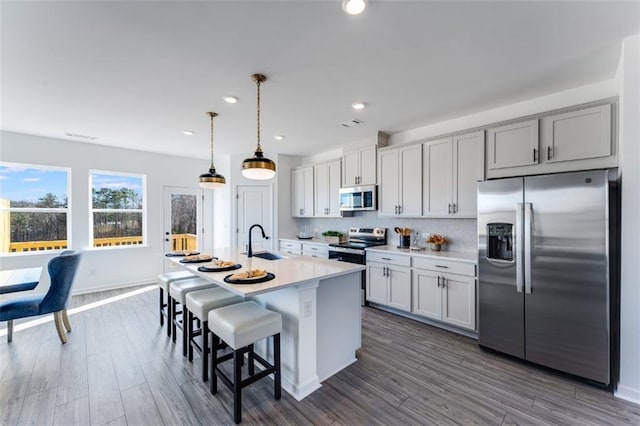 6121 Wayburn St, Tucker, GA 30084 - kitchen with appliances with stainless steel finishes, a center island with sink, light countertops, a kitchen breakfast bar, and tasteful backsplash