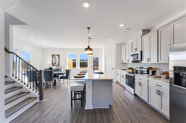 6121 Wayburn St, Tucker, GA 30084 - kitchen with stainless steel appliances, light countertops, decorative light fixtures, a kitchen island with sink, and dark wood finished floors