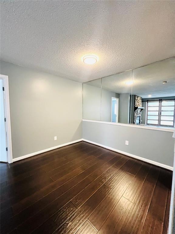 empty room featuring dark wood-style floors, baseboards, and a textured ceiling