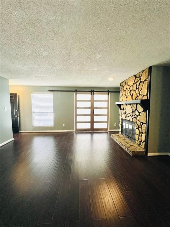 unfurnished living room with a textured ceiling, baseboards, a fireplace, and wood finished floors