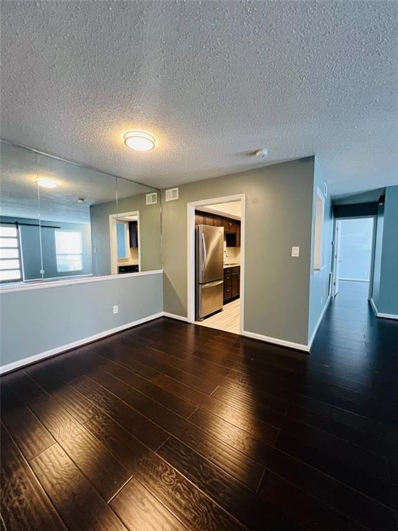 empty room with wood-type flooring, baseboards, and visible vents