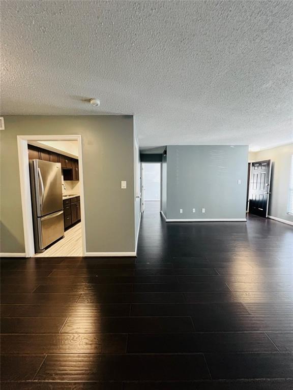empty room featuring hardwood / wood-style flooring, baseboards, and a textured ceiling