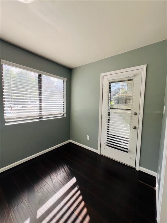 unfurnished room with baseboards and dark wood-style floors