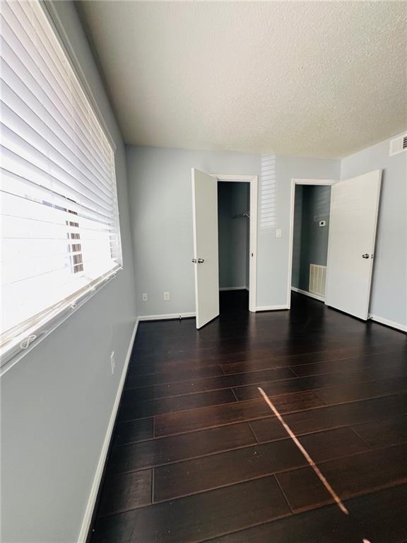 spare room with hardwood / wood-style floors, visible vents, baseboards, and a textured ceiling
