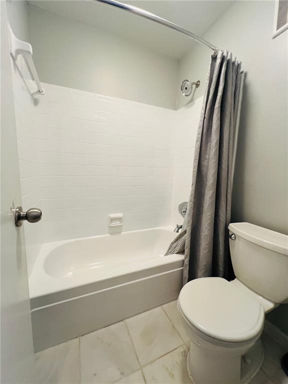 full bathroom with visible vents, toilet, shower / bath combo with shower curtain, and tile patterned flooring