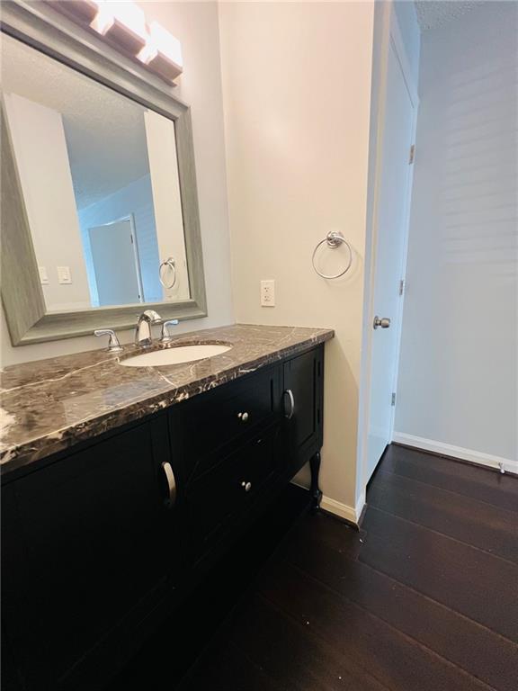 bathroom featuring baseboards, vanity, and wood-type flooring