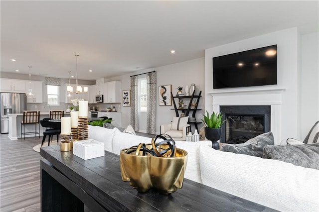 528 Aberdeen Mdw, Acworth, GA 30102 - living room featuring light wood-style flooring, an inviting chandelier, a glass covered fireplace, and recessed lighting