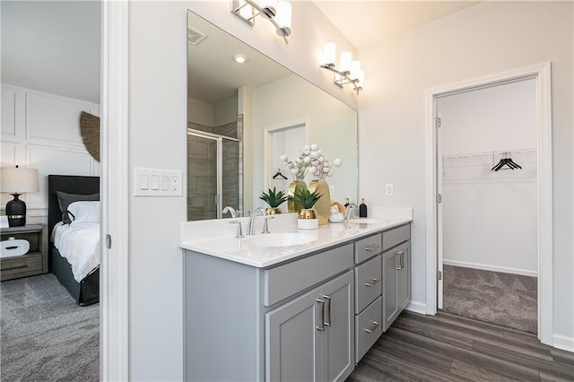 528 Aberdeen Mdw, Acworth, GA 30102 - ensuite bathroom featuring double vanity, a shower stall, a walk in closet, a sink, and wood finished floors