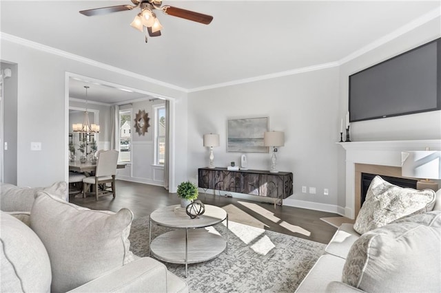 living room featuring baseboards, dark wood-style flooring, ceiling fan with notable chandelier, and crown molding