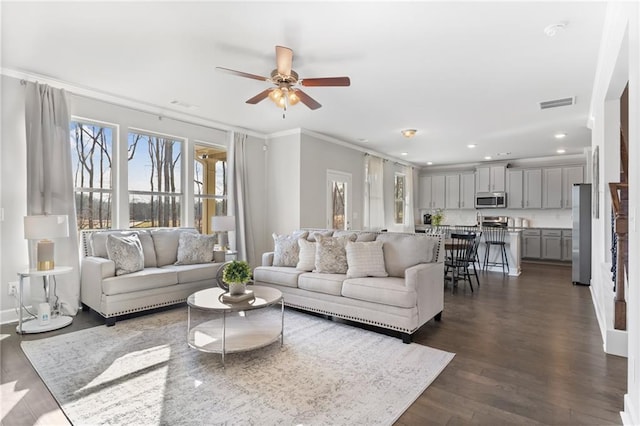 living area with visible vents, dark wood finished floors, a ceiling fan, ornamental molding, and recessed lighting