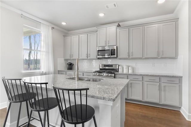 kitchen with decorative backsplash, dark wood-style floors, appliances with stainless steel finishes, light stone counters, and gray cabinets