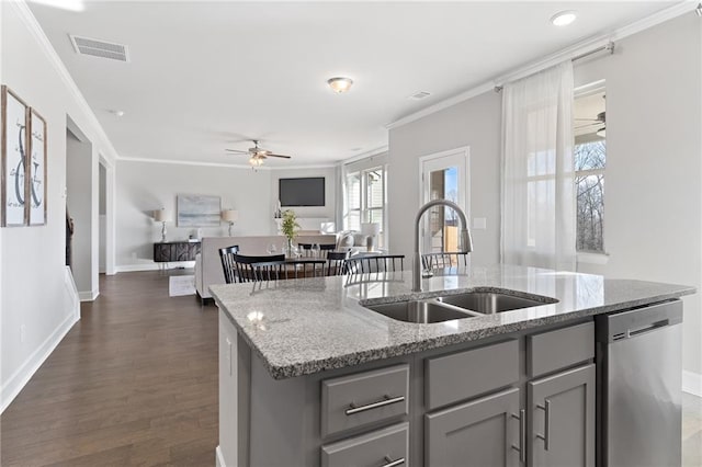 kitchen with a center island with sink, open floor plan, a sink, light stone countertops, and dishwasher