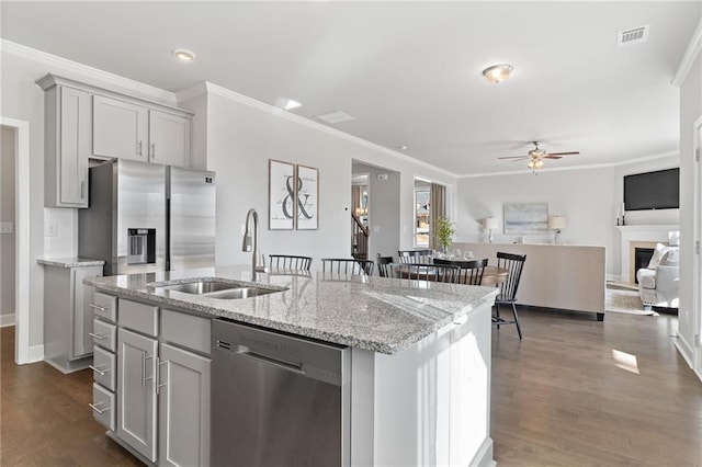 kitchen featuring an island with sink, stainless steel appliances, a sink, and open floor plan