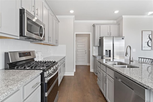 kitchen with appliances with stainless steel finishes, light stone counters, a sink, and ornamental molding