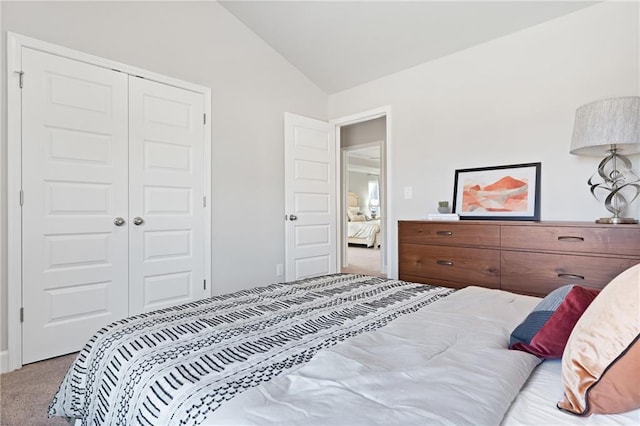 bedroom featuring a closet, light colored carpet, and vaulted ceiling