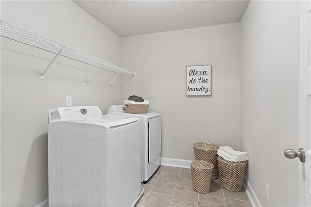 washroom with light tile patterned floors, laundry area, washer and clothes dryer, and baseboards