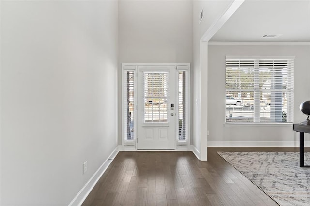 foyer entrance with baseboards, visible vents, ornamental molding, and dark wood finished floors