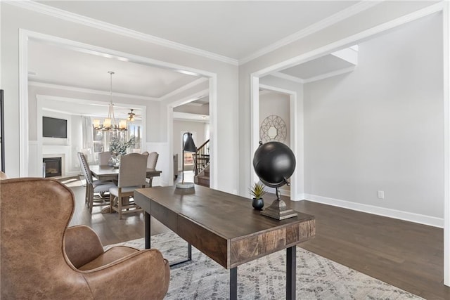 office area featuring crown molding, a fireplace, wood finished floors, baseboards, and an inviting chandelier