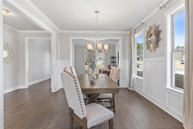 dining space with crown molding, a chandelier, a decorative wall, and dark wood finished floors