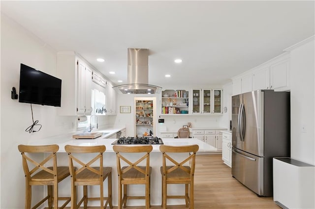 4086 Norton Pl SE, Smyrna, GA 30082 - kitchen featuring island exhaust hood, a peninsula, appliances with stainless steel finishes, light wood finished floors, and a sink