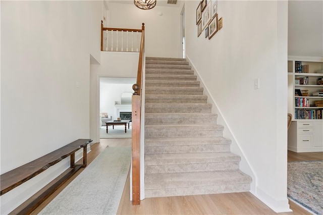 4086 Norton Pl SE, Smyrna, GA 30082 - stairs featuring a fireplace, a towering ceiling, visible vents, wood finished floors, and baseboards