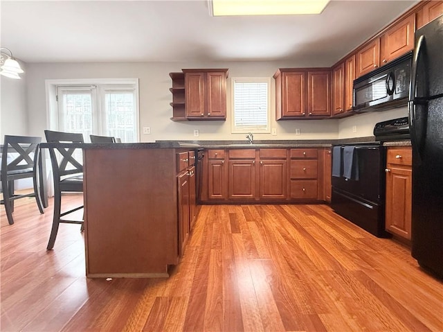 602 Summer Pl, Norcross, GA 30071 - kitchen featuring black appliances, dark countertops, light wood-style floors, a kitchen breakfast bar, and a sink