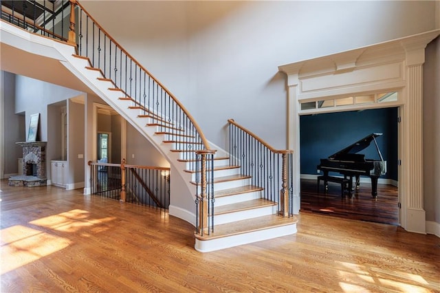 652 Pathview Ct, Dacula, GA 30019 - stairs with wood finished floors, baseboards, a high ceiling, and a stone fireplace