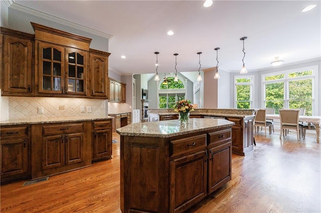 652 Pathview Ct, Dacula, GA 30019 - kitchen featuring crown molding, a center island, backsplash, glass insert cabinets, and light wood-type flooring