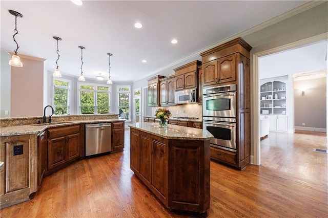 652 Pathview Ct, Dacula, GA 30019 - kitchen featuring appliances with stainless steel finishes, crown molding, a center island, a sink, and wood finished floors
