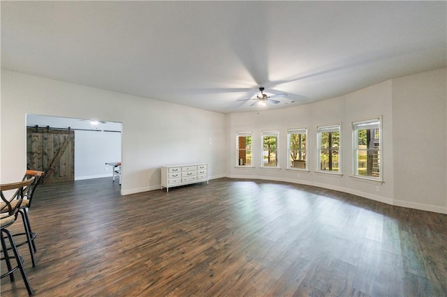 652 Pathview Ct, Dacula, GA 30019 - unfurnished living room with a barn door, dark wood-style floors, a ceiling fan, and baseboards