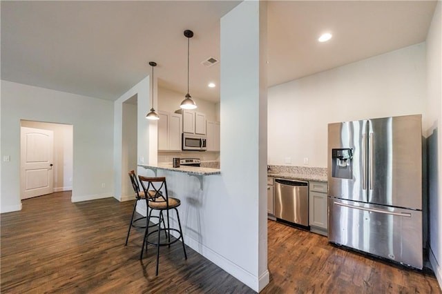 652 Pathview Ct, Dacula, GA 30019 - kitchen featuring appliances with stainless steel finishes, a kitchen bar, dark wood-type flooring, light stone counters, and recessed lighting